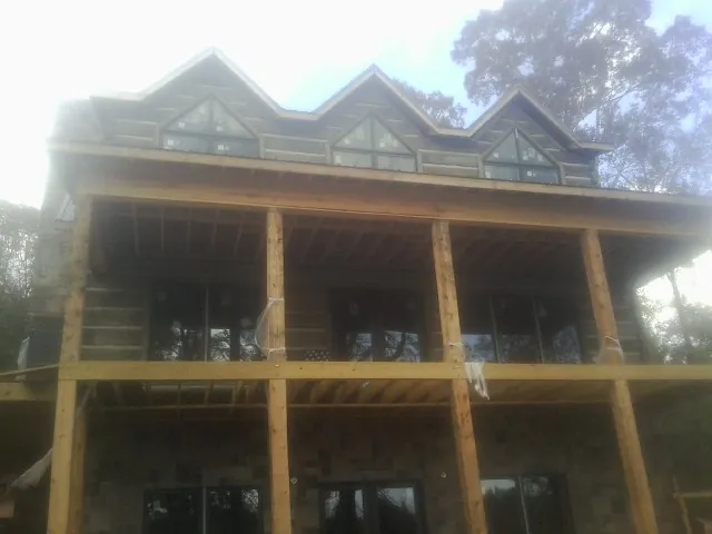 Dormers and porch framing on a large log home under construction — Roof Coating work by our crew in Stewart